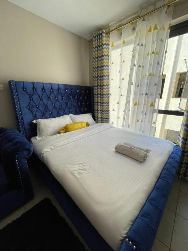 uma cama grande num quarto com uma cabeceira azul em Urban homes em Kiambu