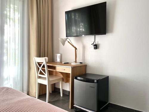 a bedroom with a desk with a television on the wall at Villa Famiri Boutique hotel in Paramaribo