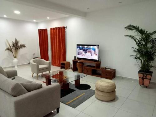 a living room with a couch and a tv at Villa d'exception à 20 min de l'aéroport 