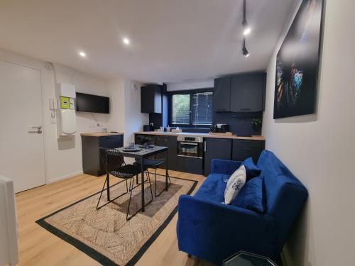 un salon avec un canapé bleu et une cuisine dans l'établissement L'Effet Papillon by Madame Conciergerie, à Bruz