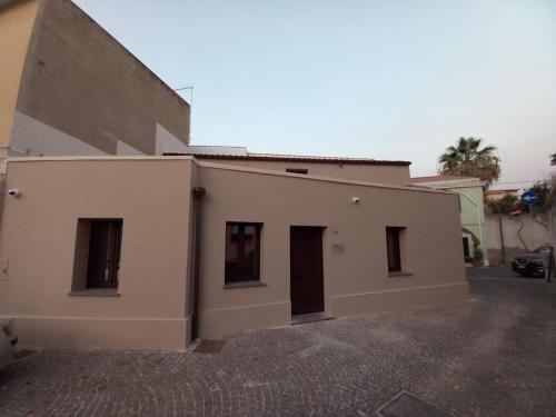 a white building with two doors on the side of it at La casetta Guest House Oristano in Oristano