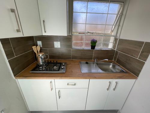 een keuken met witte kasten, een wastafel en een raam bij Spacious stay-in bachelor apartment in Kempton Park