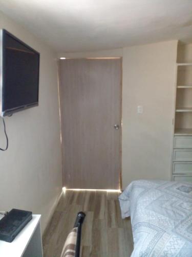 1 dormitorio con 1 cama y TV en la pared en HABITACIÓN EN ZONA RESIDENCIAL CERCA DE FASHION MALL en Chihuahua