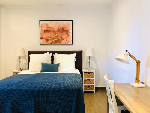 帕拉馬里博的住宿－Villa Famiri Boutique hotel，一间卧室配有一张带蓝毯的床和一张书桌
