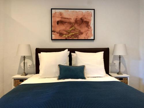 a bedroom with a bed with a blue blanket and two lamps at Villa Famiri Boutique hotel in Paramaribo