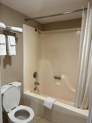 a bathroom with a white toilet and a bath tub at Travelers Rest Motel in Bogalusa