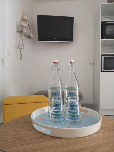 trois bouteilles assises sur un plateau sur une table dans l'établissement Appartement 4 personnes à louer, à Ouistreham