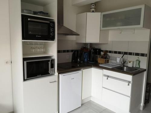 une cuisine avec des armoires blanches et des appareils noirs dans l'établissement Appartement 4 personnes à louer, à Ouistreham