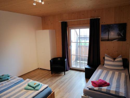 een slaapkamer met 2 bedden, een raam en een stoel bij Heidis Ferienwohnung in Linden