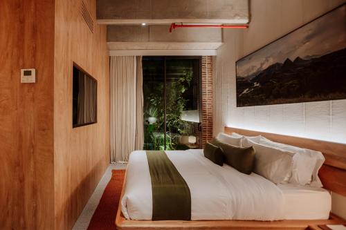 a bedroom with a large white bed with a window at Hotel El Zarzo in Medellín