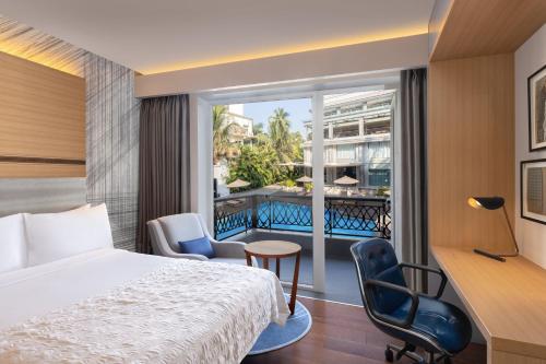a hotel room with a bed and a balcony at Le Meridien Goa, Calangute in Calangute