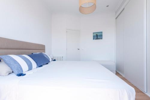 Una cama blanca con almohadas azules y blancas. en Alcalá Street View, en Madrid
