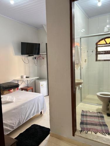 a bedroom with a bed and a bathroom with a shower at Pousada Maciel in São Thomé das Letras