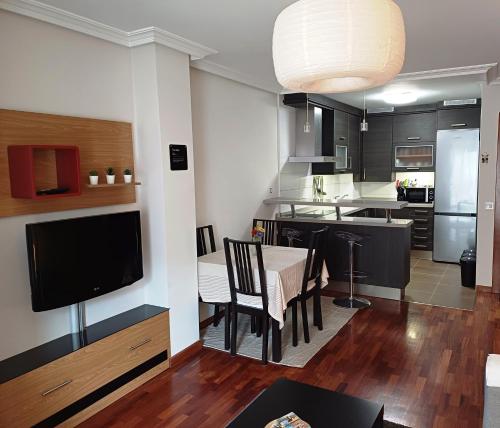 eine Küche und ein Esszimmer mit einem Tisch und einem TV in der Unterkunft Apartamento Galería Gijón in Gijón