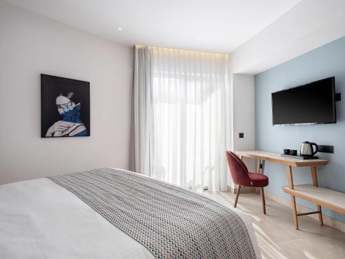 a bedroom with a bed and a desk and a television at M City Hotel in Chania Town