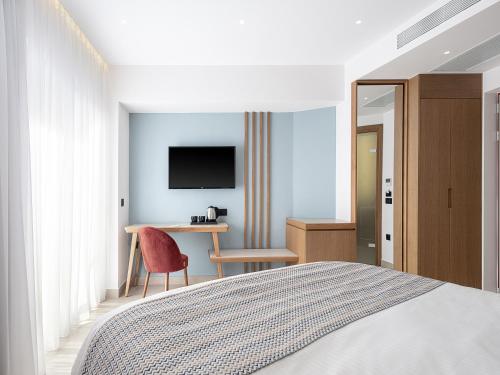 a bedroom with a bed and a desk and a tv at M City Hotel in Chania Town