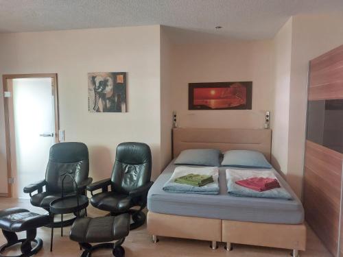 a bedroom with a bed and two chairs at Apartment GNUBBEL am Wald in Weißwasser