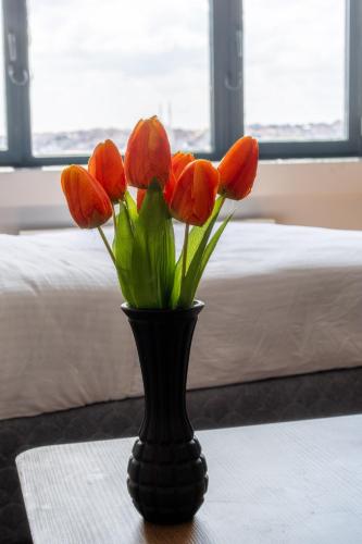 a black vase with orange flowers in it on a table at Han Residence Haliç in Istanbul