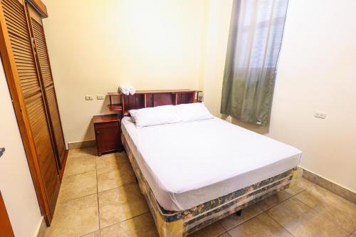 a small bedroom with a bed and a window at Sohla Rooftop Hostel in San Juan del Sur