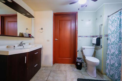 a bathroom with a toilet and a sink and a red door at Sohla Rooftop Hostel in San Juan del Sur