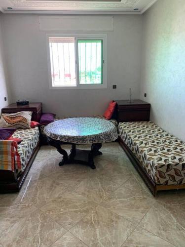 a room with two beds and a table in it at Bienvenue chez Walid in Larache