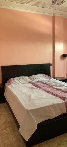 Cama en habitación con pared de color rosa en Bienvenue chez Walid en Larache