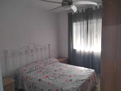 een slaapkamer met een bed en een plafondventilator bij Apartamentos Playa Holidays in Málaga