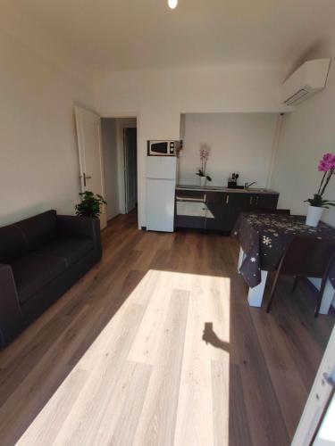 un salon avec un canapé noir et une cuisine dans l'établissement Les studios des mandariniers, à Cagnes-sur-Mer