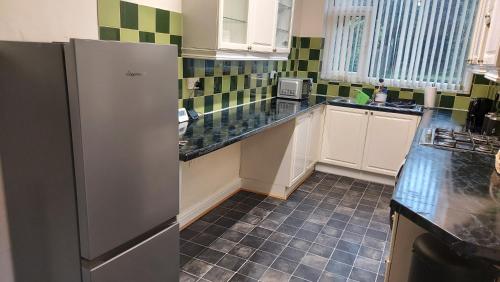 a kitchen with white cabinets and a refrigerator at HILLTOP PLACE SUITES near MEADOWHALL in Sheffield