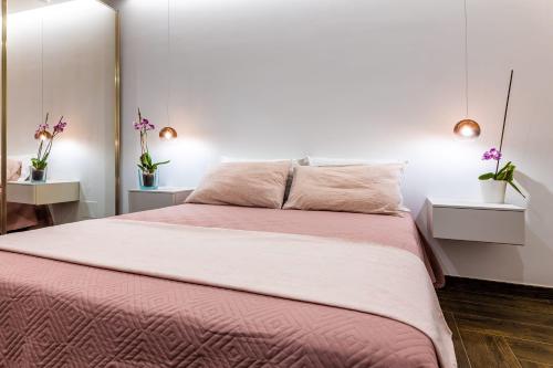 ein Schlafzimmer mit einem großen Bett mit rosa Bettwäsche und Blumen in der Unterkunft Rosina Apartment surfing bed&vacation in Terrasini