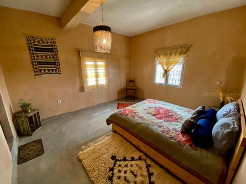 Schlafzimmer mit einem Bett, einem Teppich und Fenstern in der Unterkunft Les chandelles in Tinghir