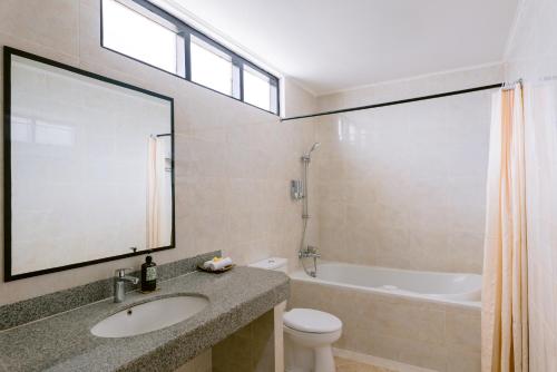 a bathroom with a sink and a tub and a toilet at Legong Keraton Beach Hotel in Canggu