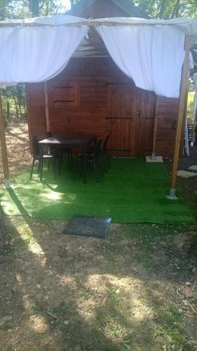 une table et des chaises sous une tente avec de l'herbe verte dans l'établissement Châlet lâché prise, 