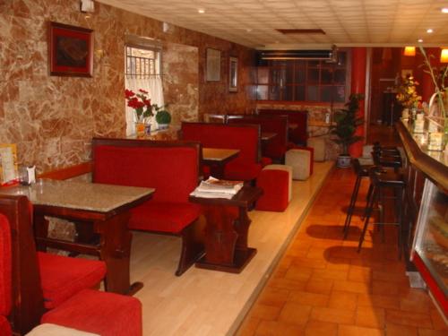 a restaurant with red chairs and tables and a bar at Hostal Restaurante Arasa in Santa Bárbara