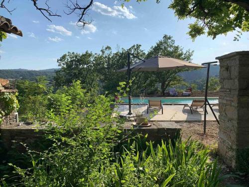 un patio avec un parasol et une piscine dans l'établissement Provencal farmhous Lubéron, swimming pool, à Revest-des-Brousses