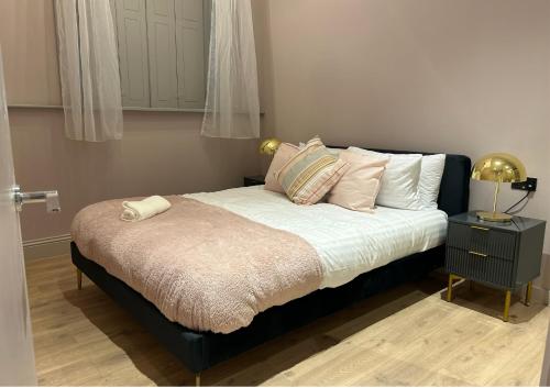 uma cama com uma moldura preta e lençóis e almofadas brancos em Bella Ruiz Penthouse in Manchester city centre em Manchester