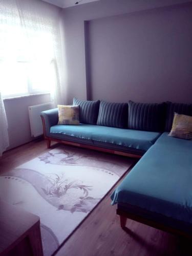 a living room with a blue couch and a rug at Ultra lüks eşyalı kiralık daire in Of