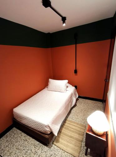 a small bedroom with a white bed and orange walls at La Bonita Guesthouse in Bucaramanga