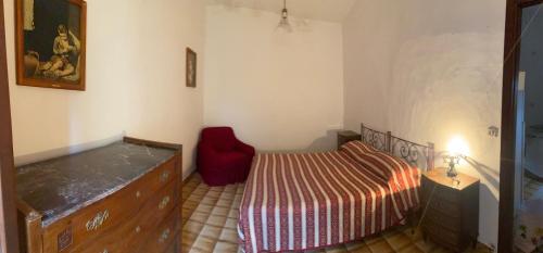 a bedroom with a bed and a red chair at La Casa nell’Antico Borgo in Alvito