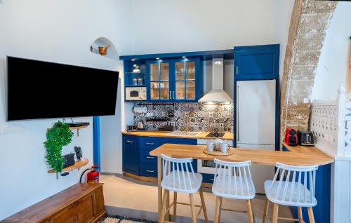 une cuisine avec des placards bleus et une table en bois avec des tabourets dans l'établissement SUN PETRADI Tradition & Luxury, à Koskinou