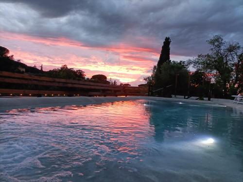 a swimming pool with a sunset in the background at Giardini Penelope Resort e Spa in Ciampino