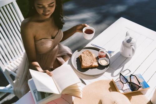 a woman in a dress reading a book with a plate of food at Legong Keraton Beach Hotel in Canggu