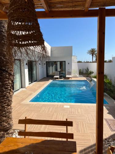 une villa avec une piscine et un banc dans l'établissement Villa de luxe sans vis-à-vis à 2 min de la plage, à Djerba