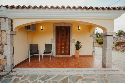 a house with a patio with two chairs at Villa Alba Sul Mare in Budoni