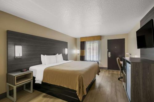 a hotel room with a bed and a flat screen tv at Quality Inn Commerce in Commerce