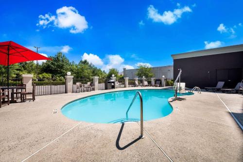 a swimming pool with a red umbrella and a table at Comfort Suites Northlake in Charlotte
