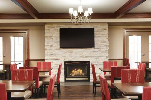 a restaurant with tables and chairs and a fireplace at Comfort Suites Milwaukee Airport in Oak Creek