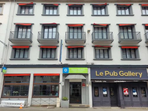 een wit gebouw met rode bogen op de ramen bij Sure Hotel By Best Western Lorient Centre in Lorient