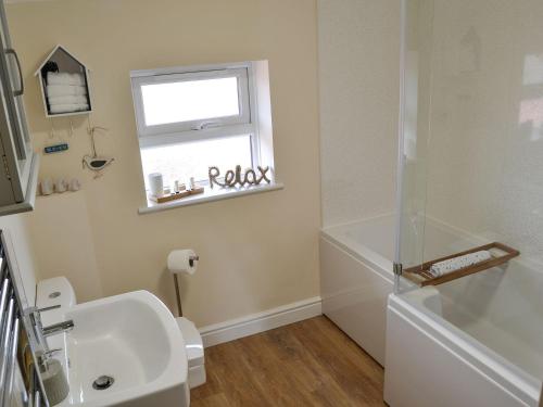 a bathroom with a sink and a toilet and a window at Sandy Toes in Mundesley