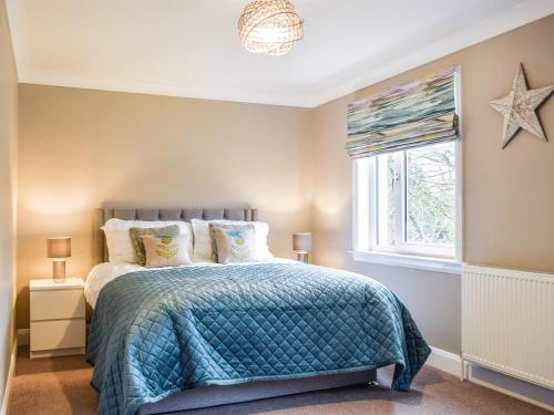 a bedroom with a bed with a blue comforter and a window at Teithbank in Callander